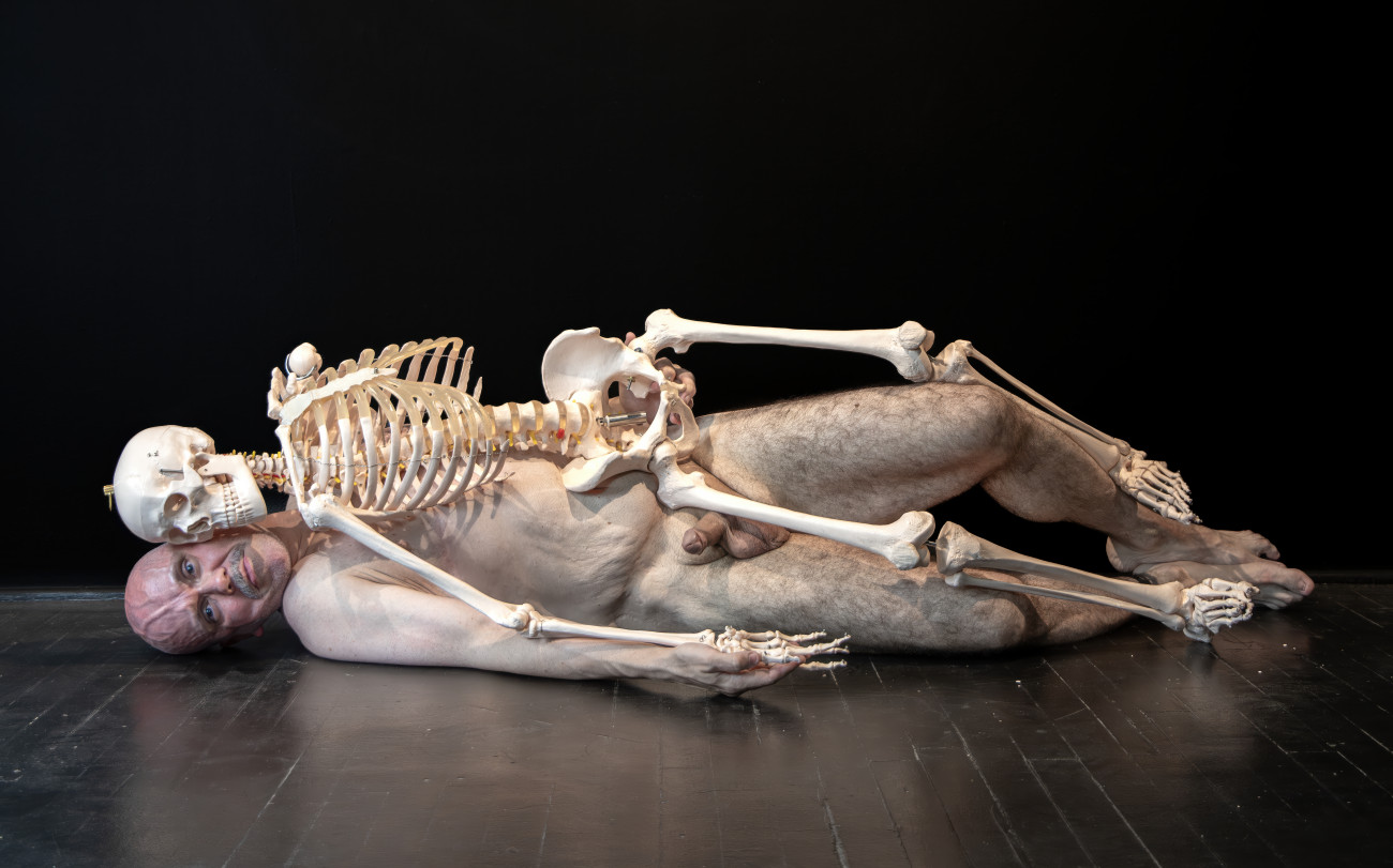 Steve Giasson. Performance invisible n&deg; 298 (&Ecirc;tre loyal au cauchemar de son choix). Reenactment de&nbsp;Marina Abramović.&nbsp;Self Portrait with Skeleton.&nbsp;2003. Performeur : Steve Giasson. Cr&eacute;dit photographique : Martin Vinette. Retouches photographiques : Charles-&Eacute;tienne Lebrun. Centre des arts actuels SKOL. 10 ao&ucirc;t 2025.